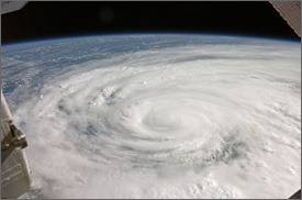 Photo from space of Hurricane Ike, a tight spiral of clouds extending over a large portion of the Earth. Parts of the International Space Station are visible in the corners of the photo.