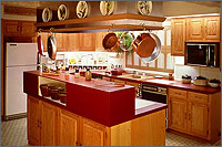 Photo of a kitchen with pots hanging over an island and multiple appliances throughout.