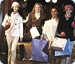 Four girls walking outside with a lot of shopping bags.