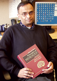 FDA neurologist and medical reviewer Dr. Ranjit Mani, M.D., sitting at his desk holding a neurology text book.