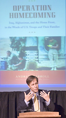 Dana Gioia at the podium with a large projection of the Operation Homecoming book cover behind him