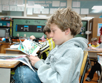 a fourth grader at St. Mary’s Catholic School in Humboldt, Iowa, reads a book handed out by Earth Team volunteers (NRCS photo — click to enlarge)