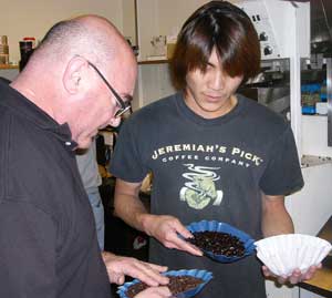A photo of two employees at Jeremiah's Pick (JP), a gourmet coffee roaster, examine freshly roasted coffee beans.