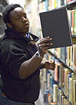 A male librarian putting a book back on the shelf.