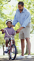 A father teaching his son to ride a bike.