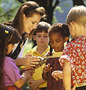 A woman showing a turtle to 2 girls and 2 boys.