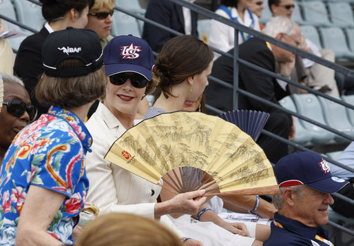 Mrs. Laura Bush wearing a U.S. Olympic baseball team hat uses a fan to keep cool as she watches the U.S. Olympic men's baseball team play a practice game against the Chinese Olympic men's baseball team Monday, Aug. 11, 2008, at the 2008 Summer Olympic Games in Beijing. White House photo by Eric Draper