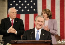 President Bush with Vice President Cheney and Speaker Pelosi standing  behind him. Click here for larger image.