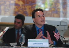 Dudas is seen speaking while seated at a table.
