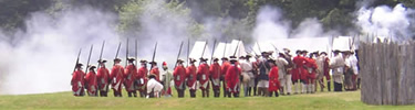 Smoke fills the air as a group British soldiers fire from inside Fort Necessity