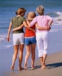 photo of a two women and a girl walking arm in arm down a beach