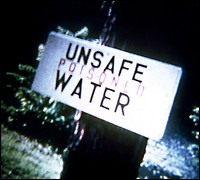 Photograph of of an unsafe water sign - stating Unsafe Poisoned Water