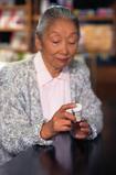 Photo of a woman reading a pill bottle label. - Click to enlarge in new window.