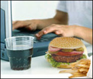 photo of a person at a computer with a hamburger and soda