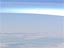A hazy view of the atmosphere as seen from space showing clouds and a curve of light