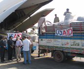 5000 blankets, 250 rools of plastic sheeting and 5,000 containers of water from USAID's pre-positioning warehouses in Dubai were airlifted to Islamabad, loaded onto Pakistani jingle trucks and delivered to Namsehra and Battagram Districts in Northern Pakistan on October 10. U.S. Ambassador Crocker and USAID DART leader Bill Berger where there to meet the plane.  The Pakistani truck drivers were determined that the USAID banner should be attached to the front of their trucks, and managed to secure them with what they had on hand. Photo: USAID