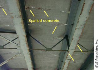 Cracking and spalling are visible on the underside of this corroded bridge deck in Albany, NY. The corrosion was caused by deicing salts that reached the black bars in the bottom mat via cracks in the deck. The yellow arrows point to six damaged areas, including through-deck cracks and places where concrete spalling exposed the corroded reinforcing steel bars.