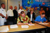 Congresswoman Ileana Ros-Lehtinen standing behind Key West Mayor MorganÂ McPherson and Assistant Secretary Woodley as they sign the project cooperation agreement for Key West. 