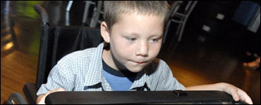 Foto: un niño en una silla de ruedas que se distrae con video juegos.