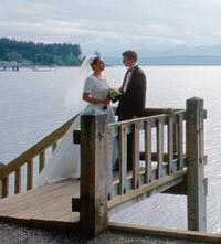 Bride and groom standing at top of stairs leading down to beach
