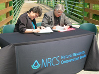 from l. Indiana NRCS State Conservationist Jane Hardisty and Plainfield Town Manager Richard Carlucci sign historic EWP agreement