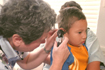 Hispanic boy has his ears examined by a physician.
