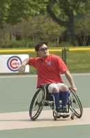 Photo of a man in a wheelchair, throwing a softball from shortstop to the first baseman.