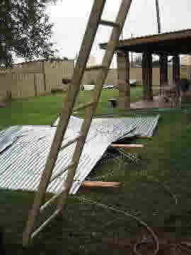 Photo of backyard of an undamaged house with debris blown from the first house, two lots east.