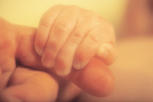 Baby’s hand holding an adult’s finger.