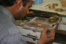 A worker in a Karachi workshop solders gold bangles with a gas flame.