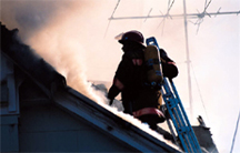 Photograph of firefighter on smoking roof.