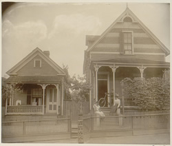 Gelatin silver print showing African American boy seated on porch of house