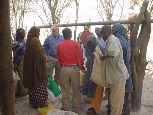 Acting Assistant Secretary Witten inspecting the weighing of individual food rations by refugee committee members to ensure that all refugees receive their expected allocations. [State Dept. Image]