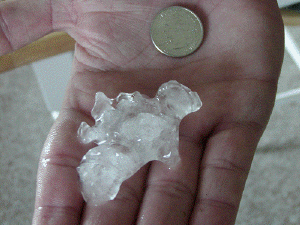 Large hailstone and a quarter in the palm of a hand