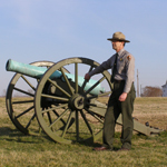 A ranger stands next to a cannon at Malvern Hill battlefield.