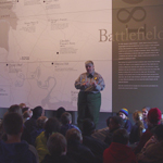A ranger talks in front of a map to a group of elementary school children.
