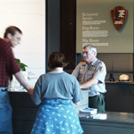 A ranger talks to two visitors at the orientation desk.