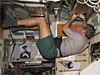 An astronaut dressed in shorts and a t-shirt floats in microgravity while he works on equipment on the ISS