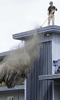 photograph of man sweeping volcanic ash off a rooftop in Anchorage, Alaska