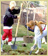 [Photo]: Boy and girl digging a hole to plant a tree.