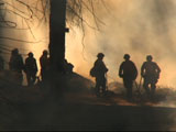 Firefighters and smoke backlit by fire