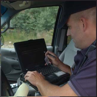 Photograph of police officer conducting a driver's license check on his patrol car computer