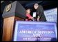 President George W. Bush shakes the hand of Jonnie Nance, chairman of the Joint Armed Forces Officers' Wives Luncheon, after being introduced by her Tuesday, Oct. 25, 2005, at the Bolling Air Force Base Officers' Club in Washington, D.C. The President told the audience that he understood it was a trying time for military spouses, adding: "By standing behind those who serve, you're serving, as well."  White House photo by Paul Morse