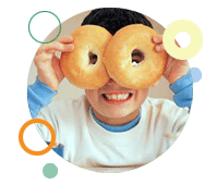 Image of young boy holding two bagels over his eyes