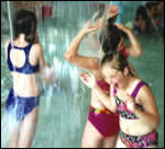 Tres ninas jugando en una cascada de la piscina.