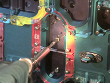 Close-up of an astronaut's hand removing screws from the cover of STIS with the fastener capture plate