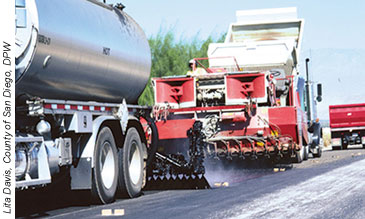 Workers are placing a chip seal on pavement, a common preventive maintenance treatment to help restore the surface characteristics of pavements in good condition.