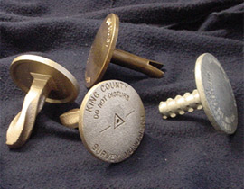 Photo:  A variety of brass and aluminum disks for setting in rock or concrete.