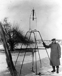Dr. Goddard standing next to his rocket.
