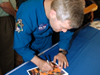 STS-122 Commander Steve Frick signs a crew photograph at Kennedy Space Center.